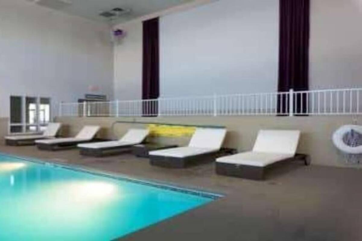 Una piscina interior con sillas de descanso y una barandilla de seguridad blanca.