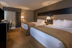 A hotel room with two beds, a desk, a chair, and a television.