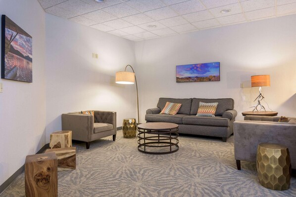 Una sala de estar moderna con un sofá gris, dos sillones, una mesa redonda y una alfombra estampada.