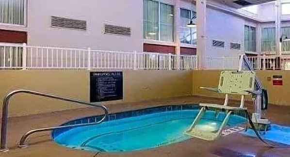 Una piscina interior con trampolín, una silla de salvavidas y un cartel en la pared.
