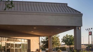A building with a large overhang, a glass entrance, and a sign indicating a parking area. - Ramada by Wyndham Boise (Boise)