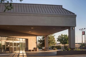 Un edificio con un gran alero, entrada de vidrio y un letrero que indica un estacionamiento.