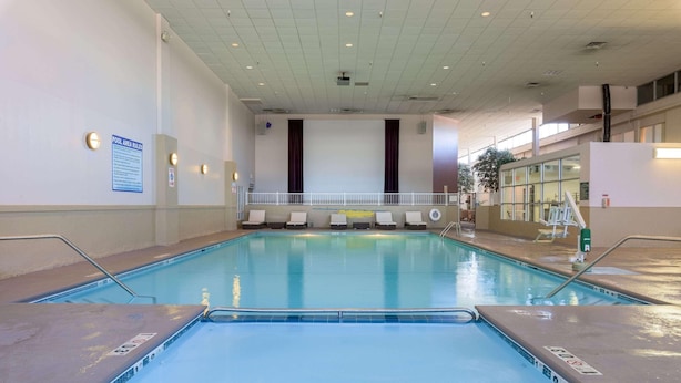 An indoor swimming pool with clear water, a pool area rule sign, and a white railing. - Ramada by Wyndham Boise (Boise)