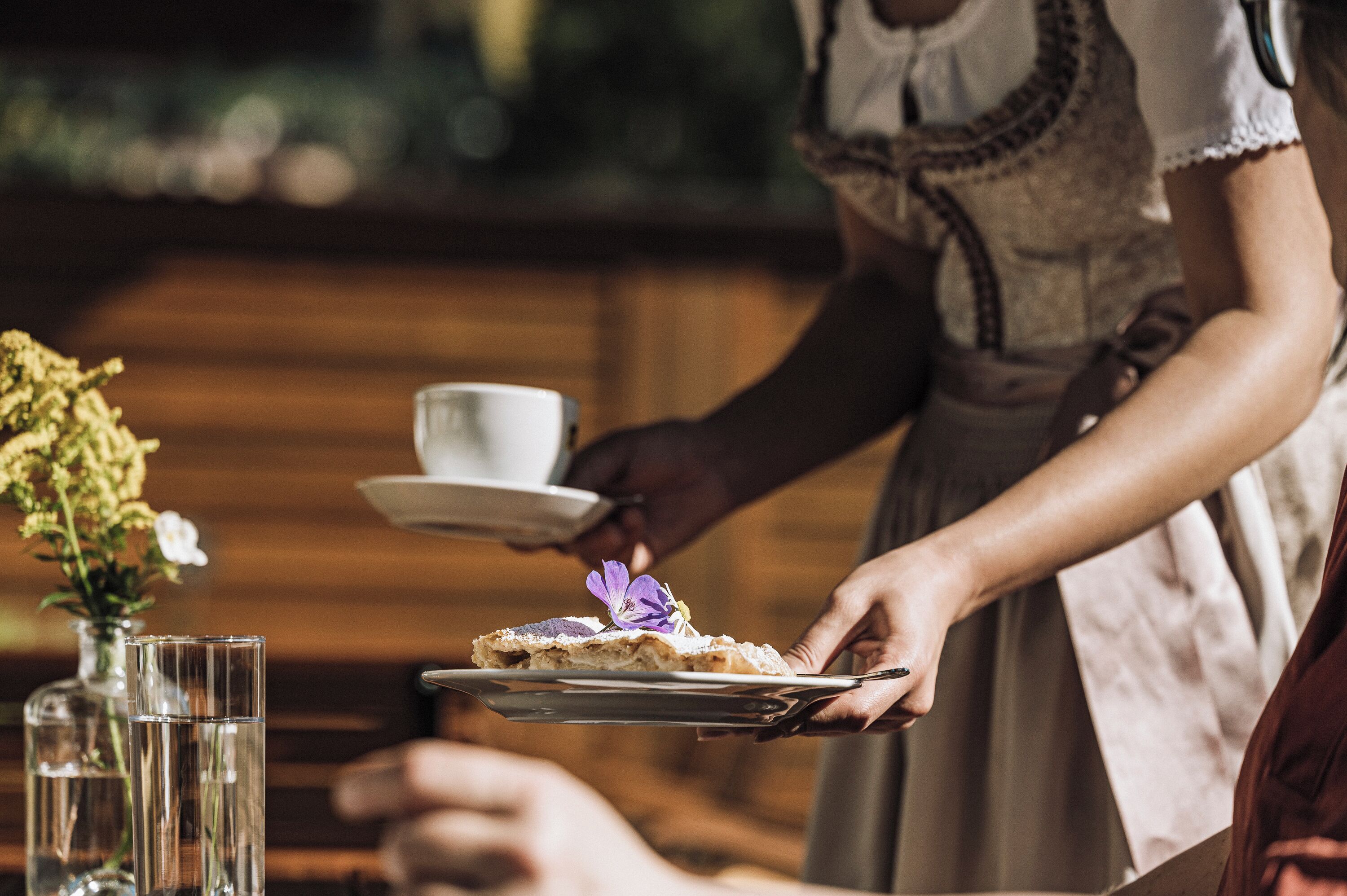Una persona sirviendo una porción de pastel con una flor en un plato.
