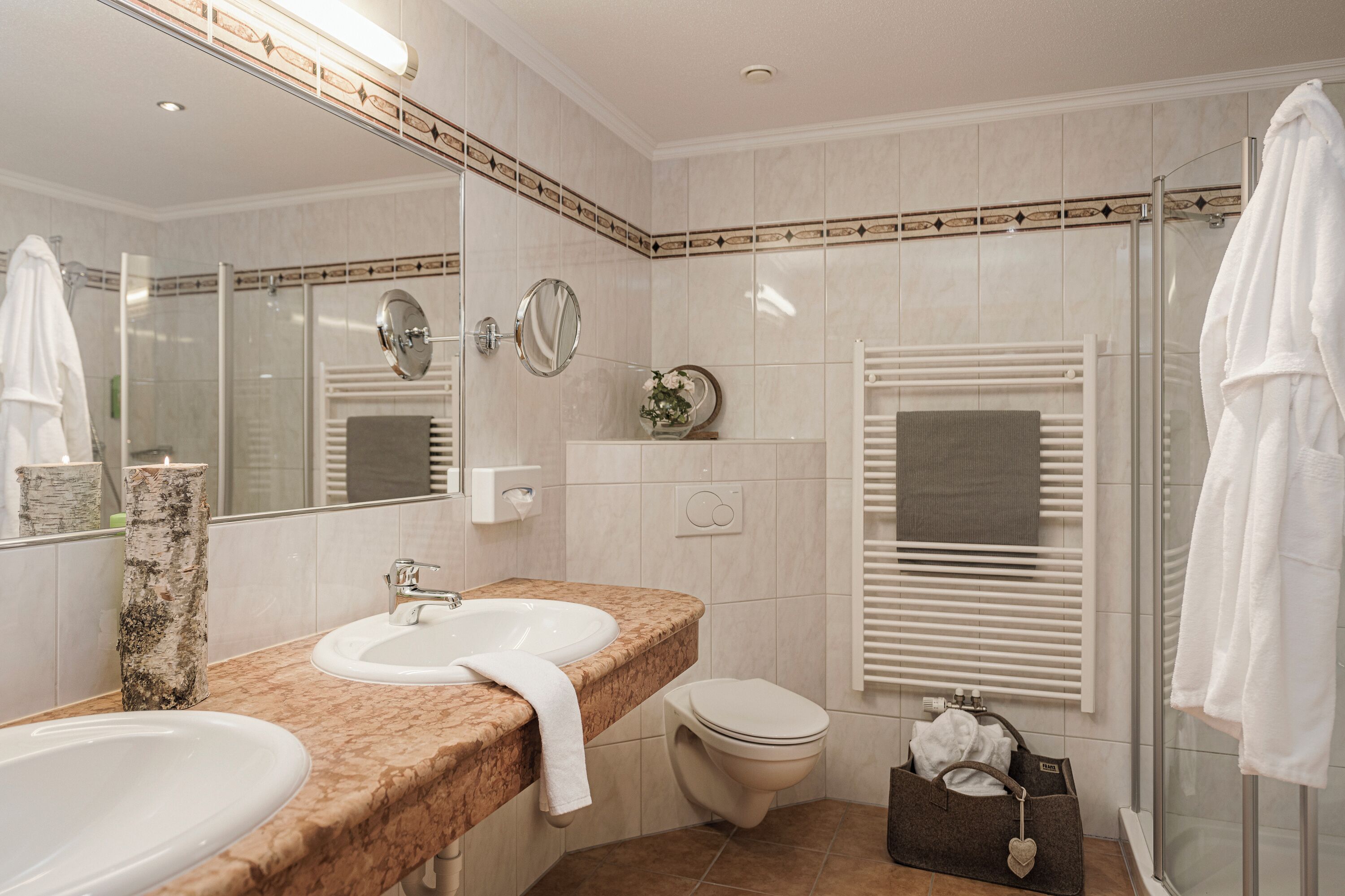 A modern bathroom with two sinks, a toilet, and a glass shower enclosure.