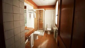 Ein schmales Badezimmer mit Dusche, Toilette und Waschbecken.