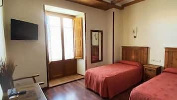 Una habitación con dos camas, vigas de madera en el techo, un escritorio y una ventana.