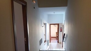 Ein Korridor mit gefliestem Boden, einer Tür links und einer Treppe, die in einen anderen Raum führt.
