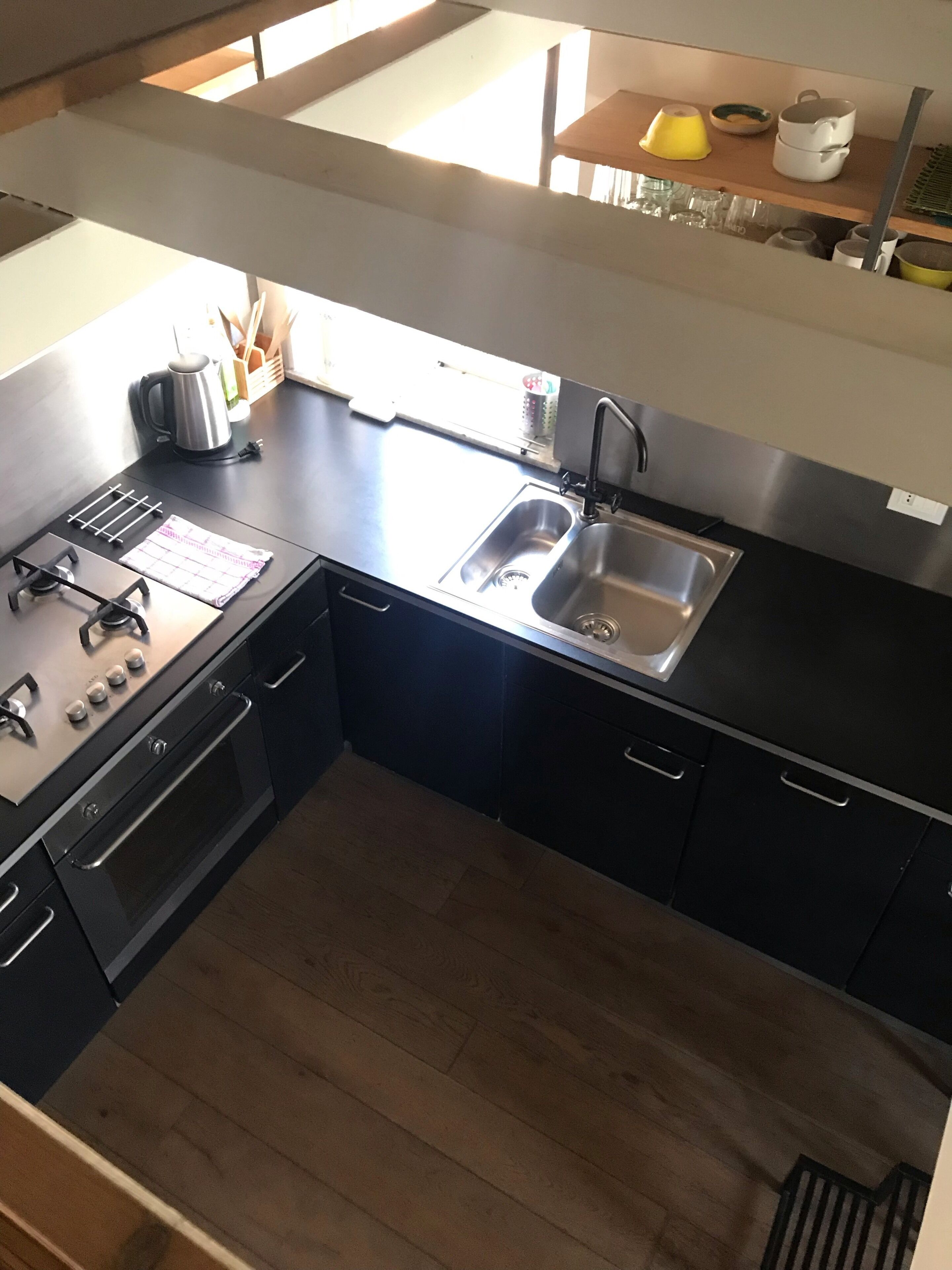 A modern kitchen with a stainless steel sink, a kettle, and a stove.