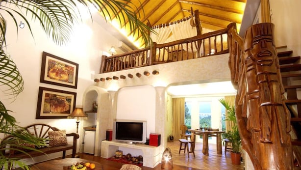 Un amplio salón con una escalera de madera, un televisor y una mesa de comedor con sillas.
