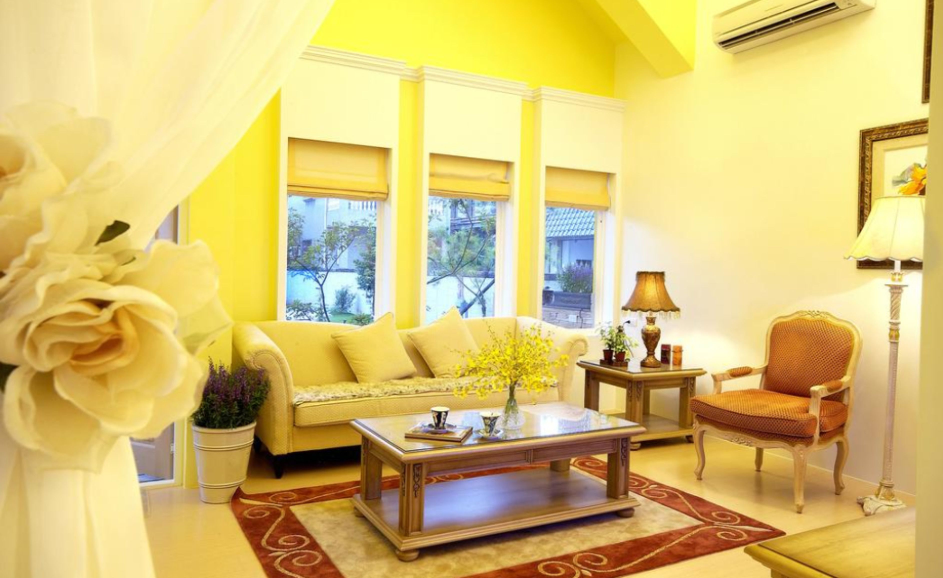 Una sala de estar con sofá, sillón, mesa de centro y ventana con vista a la vegetación.