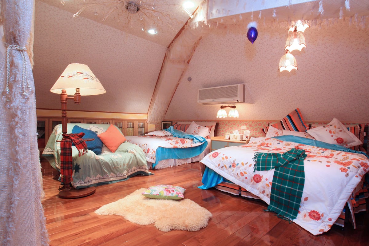 A cozy bedroom with two beds, a wooden floor, and a ceiling fan.