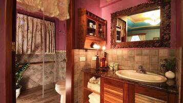 A bathroom with a wooden vanity, a mirror, and a shower area with a curtain.