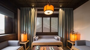 A room with a sofa, two lamps, a table with teaware, and a window with a lattice design. - Lijiang Zhuyun boutique Hotel (Lijiang)