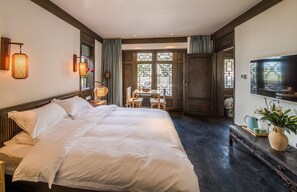 A spacious bedroom with a large bed, a dining area, and a TV. - Lijiang Zhuyun boutique Hotel (Lijiang)