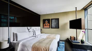 A modern hotel room with a large bed, a flat-screen TV, a desk with a lamp, and artwork on the walls.