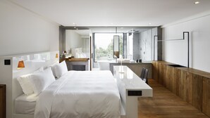 Habitación de hotel moderna con una cama grande, un escritorio de madera y vistas al exterior.