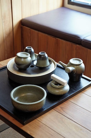 A traditional Japanese tea set on a tray, placed on a wooden table in a room with a cushioned bench. - Xiamen Hotel Wind (Xiamen)