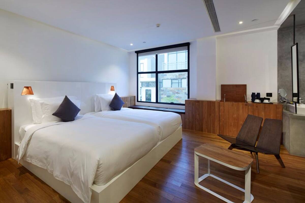 Une chambre d’hôtel moderne avec un grand lit, un petit bureau, une chaise et une fenêtre donnant sur un beau paysage.