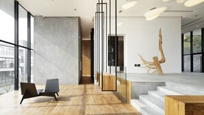 Un interior moderno con suelo de madera, una silla negra, un mostrador de recepción y una escalera.