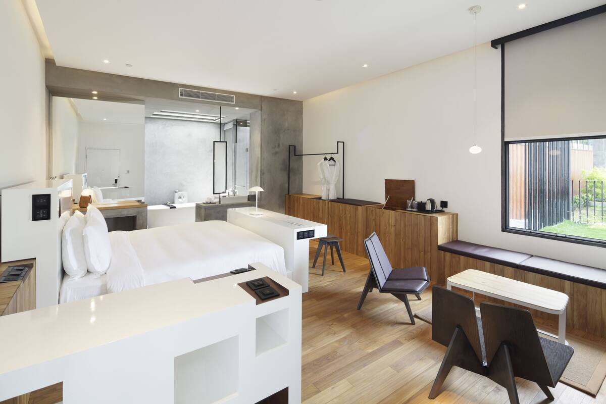 Une chambre d’hôtel moderne équipée d’un lit, d’un bureau, d’une chaise et d’une grande fenêtre.
