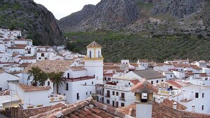 Une ville côtière aux bâtiments blancs, aux toits en tuiles de terre cuite et à l’imposante église surmontée d’un toit jaune.