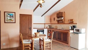 Une cuisine compacte comprenant une table à manger en bois, des chaises, un petit réfrigérateur et un four à micro-ondes.