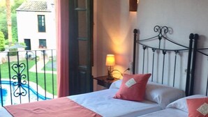 Une chambre d’hôtel avec deux lits, un balcon donnant sur une piscine et une vue sur un bâtiment situé à l’extérieur.