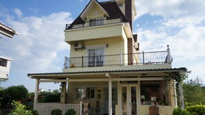 Une maison à deux étages avec un balcon, une véranda et une porte d’entrée.