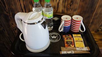 Una bandeja con una tetera blanca, dos botellas de agua, dos tazas con diseños de la bandera estadounidense y sobres de té Twinings.