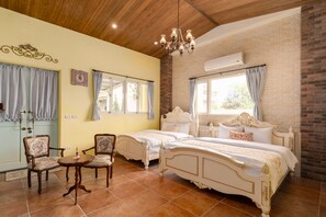 A bedroom with two beds, a chandelier, and a brick wall. - Brulees Done (Dongshan)