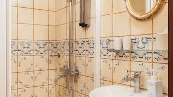 Une salle de bain avec une douche, un lavabo et un miroir.