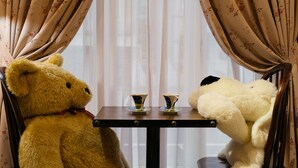 Deux ours en peluche sont assis à une petite table devant deux tasses.