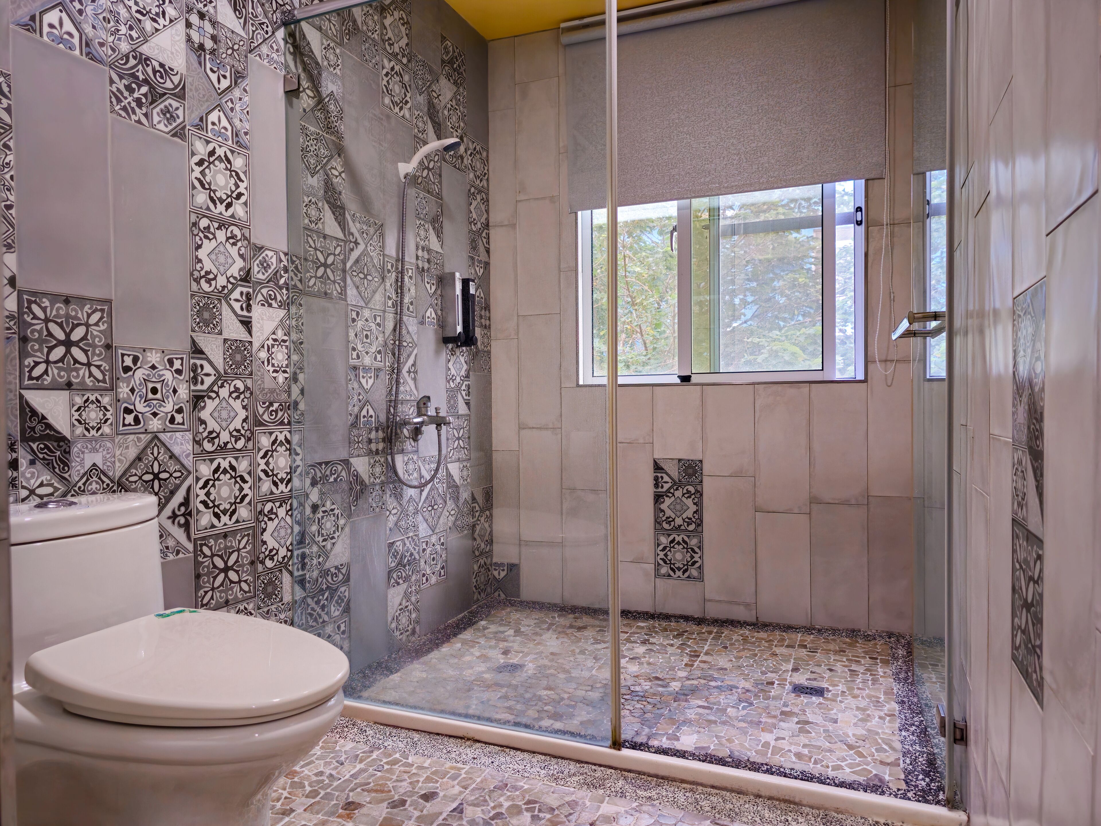 A bathroom with a shower, a toilet, and a window.