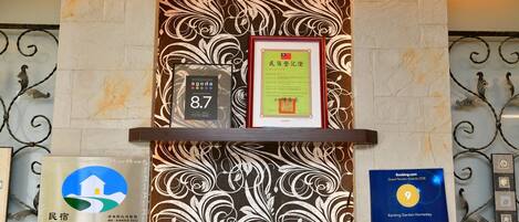 A reception area with a marble wall, framed certificates, and a rating sign.