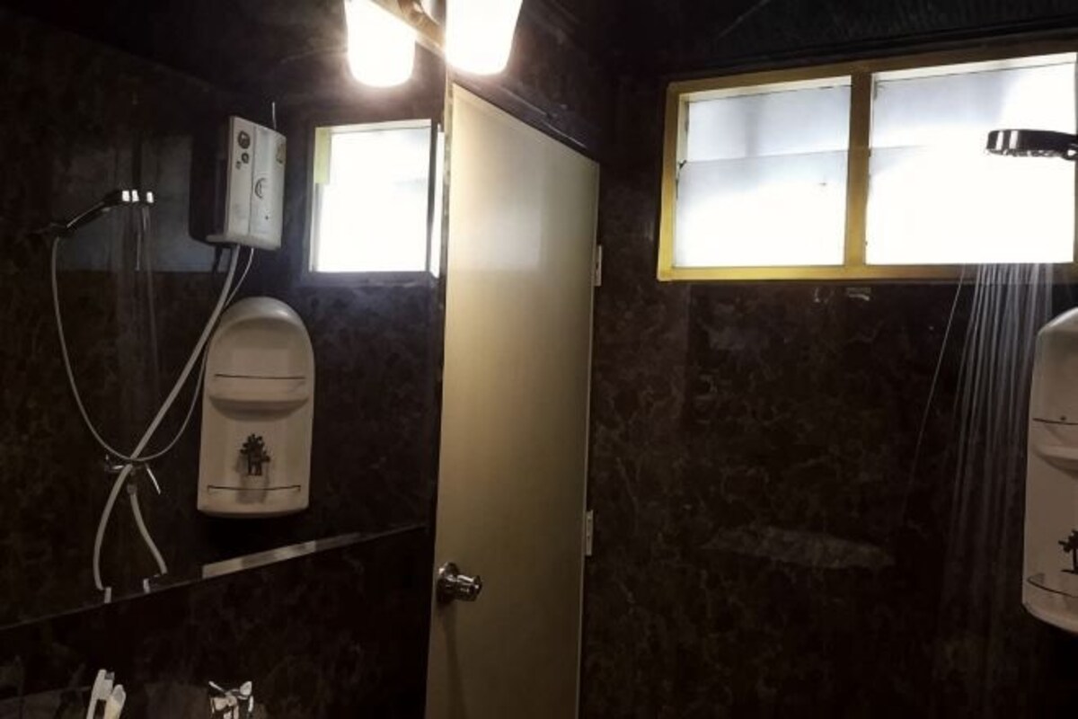 A bathroom with a shower, a toilet, a sink, and a mirror.