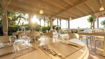 An outdoor dining area with tables set for a meal, surrounded by greenery and overlooking a scenic view.