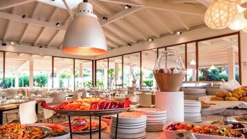 Un buffet con diversi piatti, un soffitto bianco con luci a sospensione e vista su del verde all'esterno.