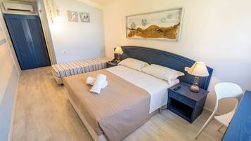A hotel room with a bed, bedside tables, a chair, and artwork on the wall.