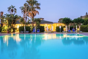 Una piscina con sillas de descanso y palmeras.