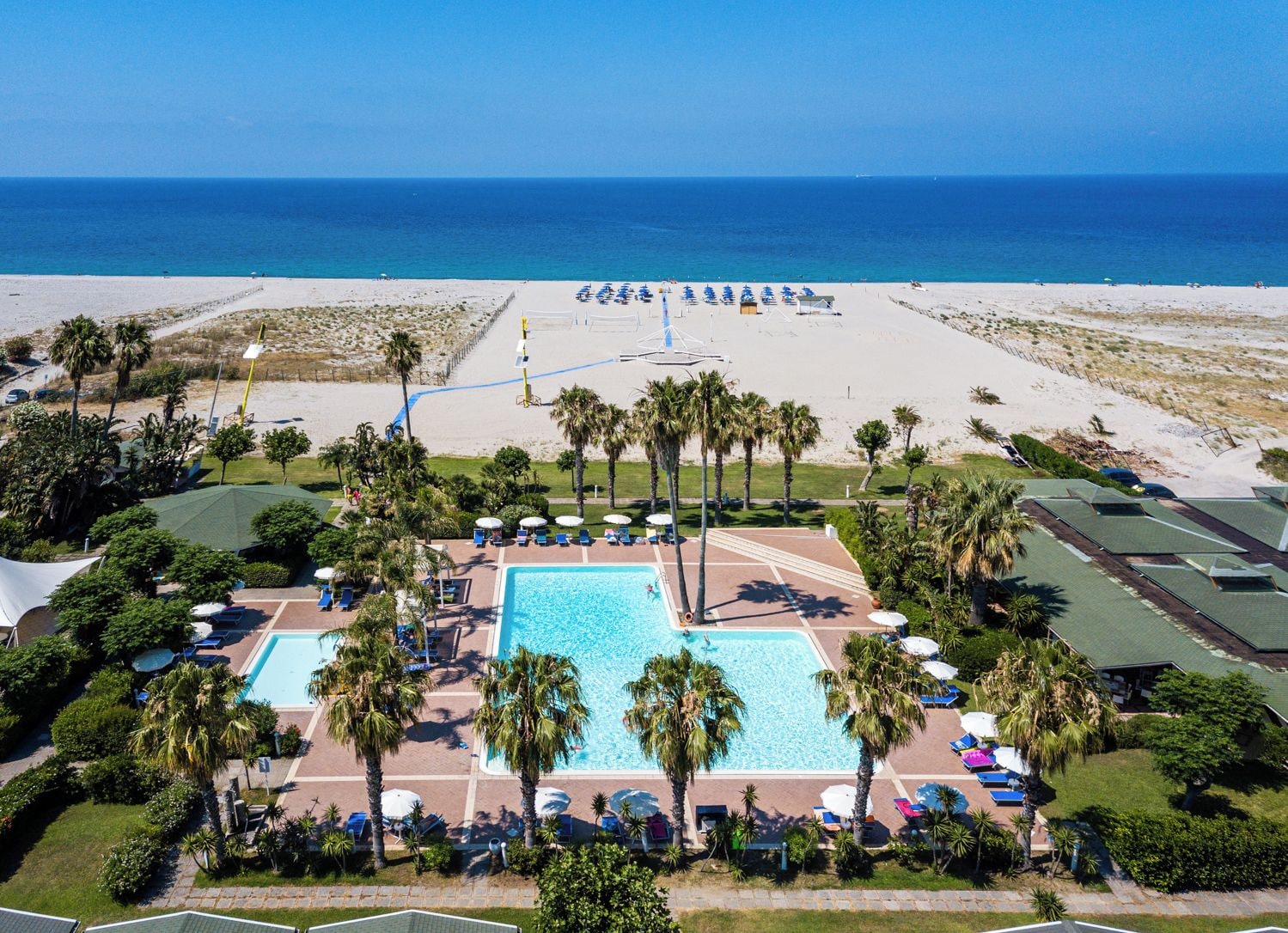 Un resort con una grande piscina, accesso diretto alla spiaggia e palme.