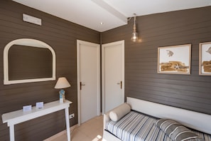 A bedroom with a bed, a bedside table with a lamp, a mirror, and two framed pictures on the wall. - Le Dune Beach Club (Messina)