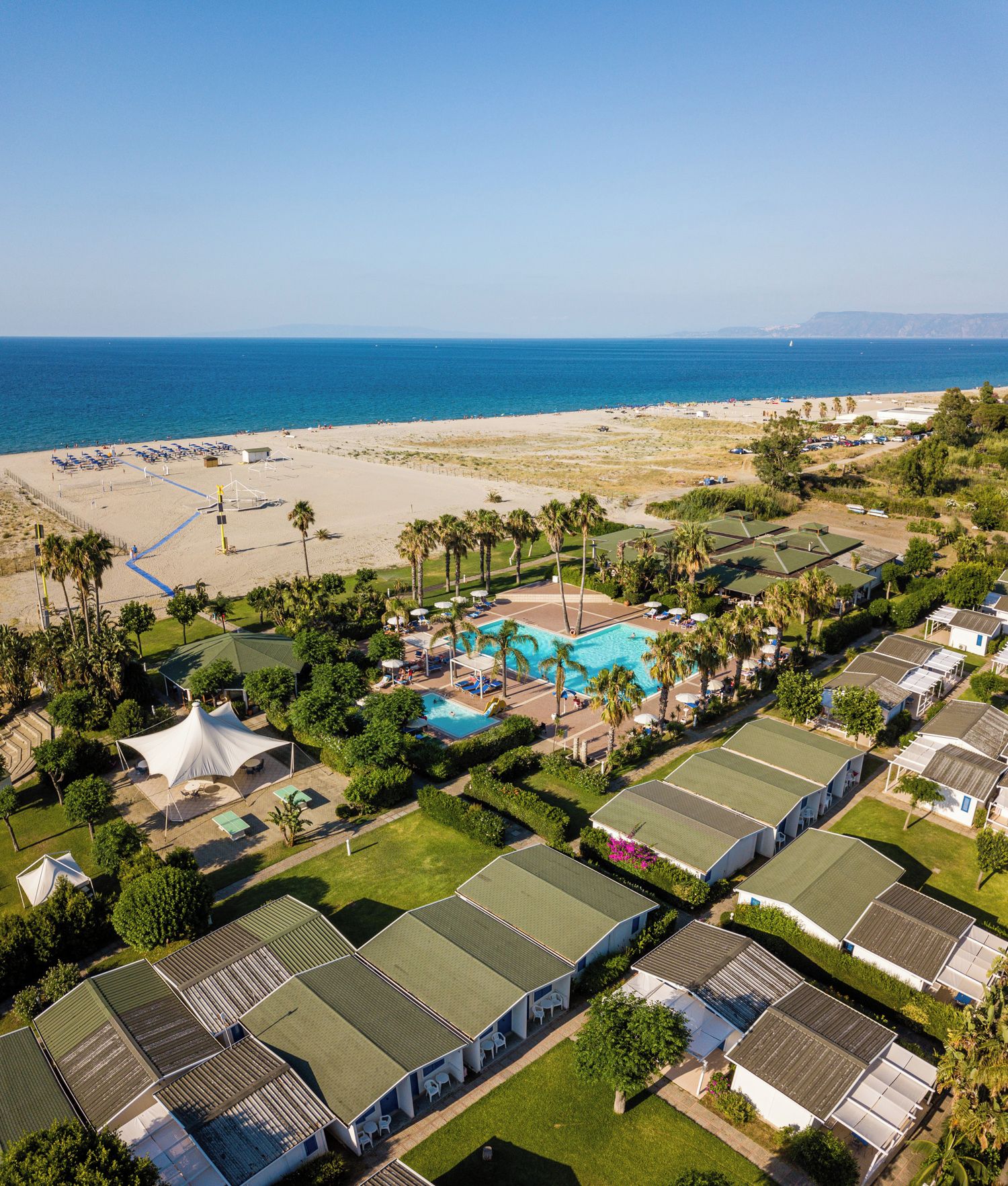A resort with multiple bungalow-style accommodations, a central swimming pool, and a beach area.