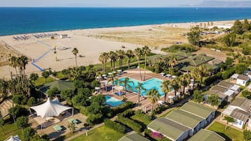 A resort with multiple bungalow-style accommodations, a central swimming pool, and a beach area.