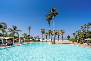 A clear blue pool surrounded by palm trees and lounge chairs. - Le Dune Beach Club (Messina)