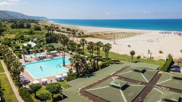 Un resort con piscina, spiaggia e palme.