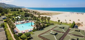 Un complexe hôtelier doté d’une piscine, d’une plage et de palmiers.
