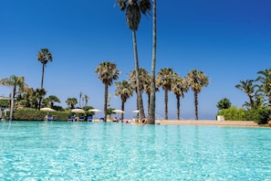 A clear blue pool with lounge chairs and umbrellas, surrounded by tall palm trees. - Le Dune Beach Club (Messina)