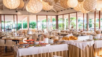 Un ristorante con numerosi tavoli apparecchiati per consumare, con un buffet che offre diversi piatti.