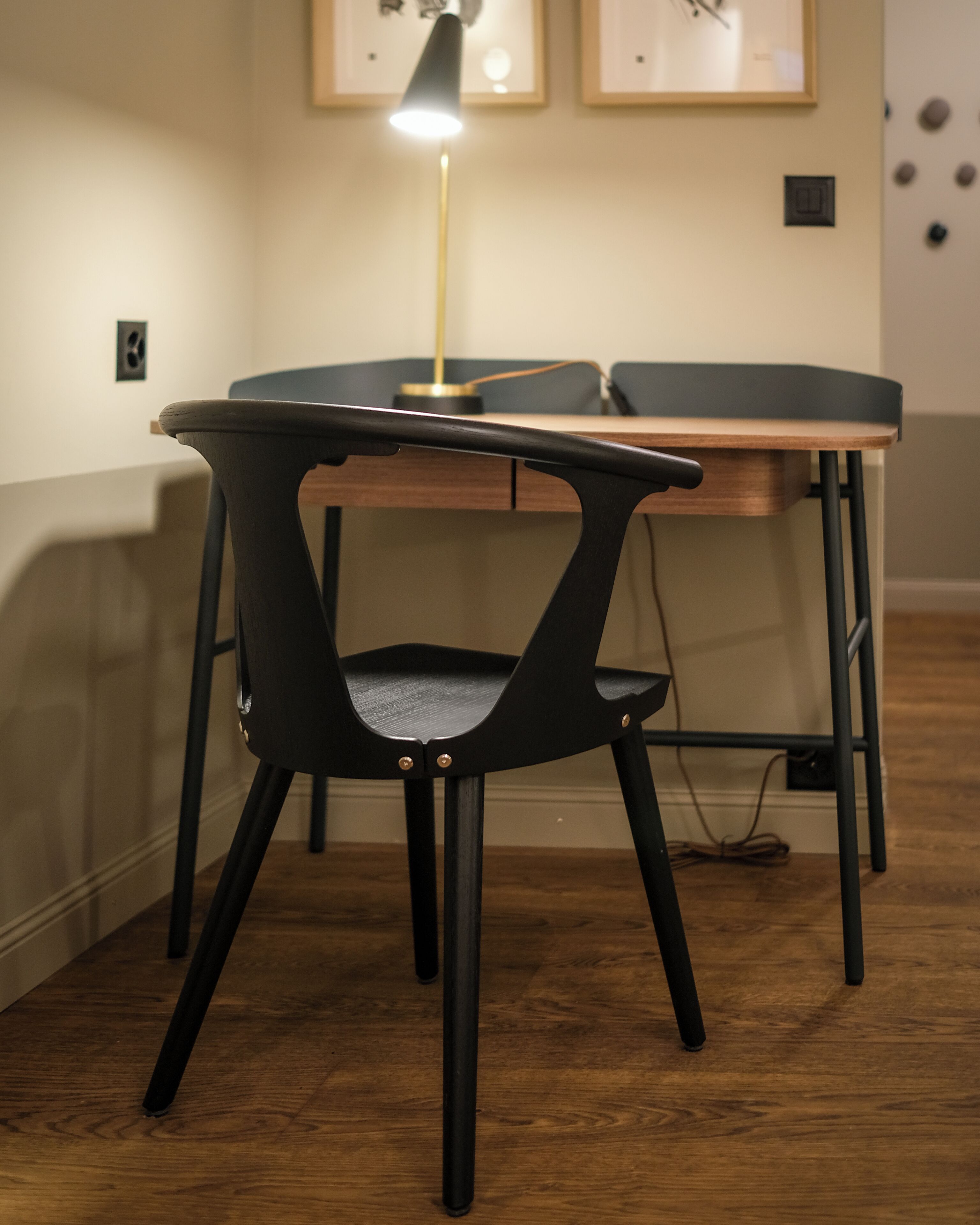 Een moderne kamer met een houten tafel en een zwarte stoel met een netrug.